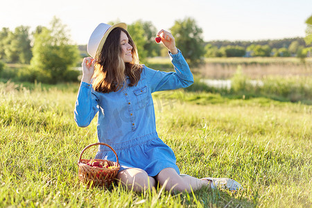穿着牛仔布礼帽的漂亮少女吃着成熟的草莓