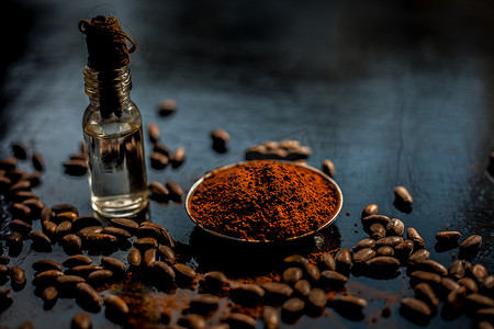 包药摄影照片_黑色木质表面抗衰老的咖啡面膜，由一些咖啡豆和生有机椰子油组成，装在一个小玻璃瓶中。