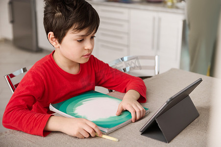 青春期前的小学生在家里用数字平板电脑做作业。