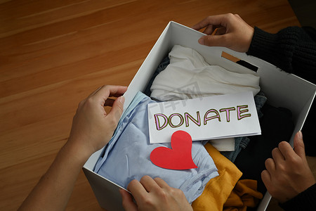 年轻志愿者拿着装有衣服和捐赠字样的盒子的最高视图。