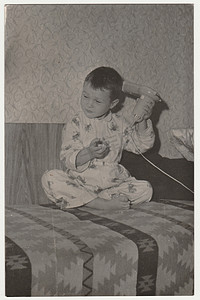 复古照片显示一个小男孩穿着睡衣，他使用吹风机。