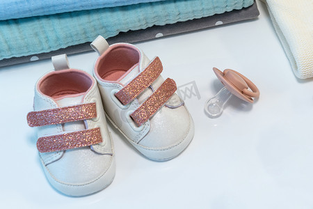 女婴粉红色鞋子与白色表面上的其他新生婴儿配件。