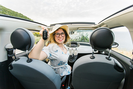 奥迪tt车钥匙摄影照片_戴着夏日帽子的女性司机拿着车钥匙驾驶她的新车敞篷车 — 汽车和购买概念