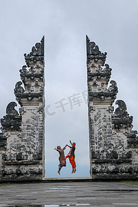 寺庙大门摄影照片_快乐的年轻夫妇在天堂的寺庙大门中跳跃。