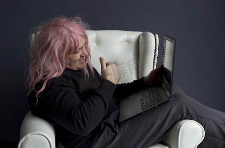 一个戴着粉色假发的男人坐在椅子上，通过视频链接进行交流。
