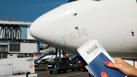 特写镜头，女性手拿着航空公司登机牌票、登机牌和护照在机场，在飞机的背景