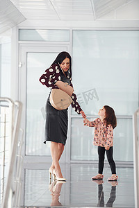 年轻的母亲带着女儿在办公室或机场在室内散步。