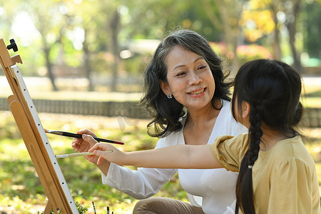 积极成熟的祖母和小孙女画画，一起在户外享受休闲周末爱好活动