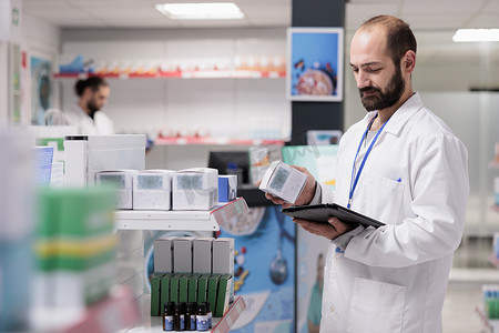 药店员工查看药品包装，在盘点期间在平板电脑上输入药品名称