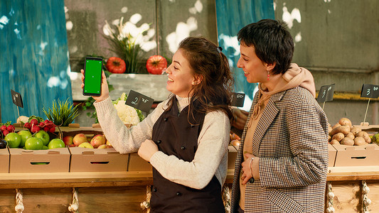 苹果手机样机模板摄影照片_两名女性在智能手机上查看绿屏显示屏