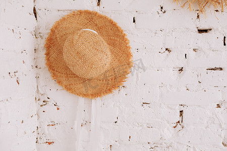 白色砖墙背景上的一顶草帽，带有复制空间。