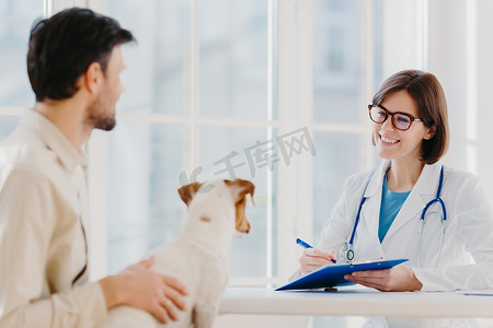 男人带着他的宠物去诊所进行兽医检查，告诉他生病的狗的症状。