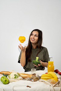穿着绿色 T 恤的快乐女人在家里的厨房里打开购物网状生态袋，里面装着健康的蔬菜、水果、面包、零食。
