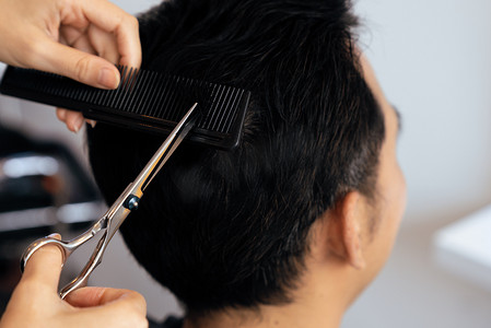 合格的女理发师在合格的美发沙龙为男性顾客理发。