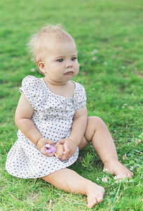 穿着圆点裙的可爱宝宝在公园里玩洋娃娃