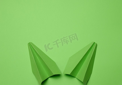 绿色折纸导航摄影照片_在绿色背景的绿色纸飞机，旅行概念，顶视图。