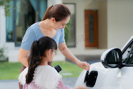 EV 汽车和充电站的母亲和女儿的进步生活方式。