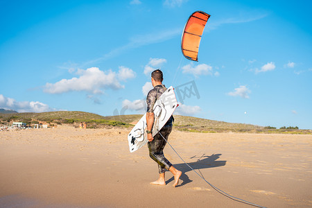 肖像波浪风筝冲浪者带着他的冲浪板和风筝在海滩散步