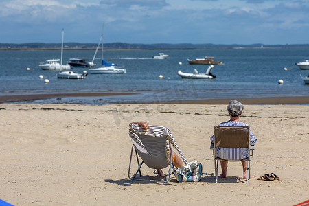 老年夫妇坐在长椅上看海