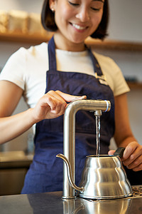 咖啡厅女咖啡师从水龙头倒水，用水壶冲泡过滤咖啡的垂直镜头