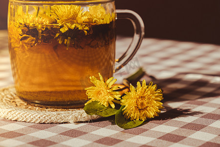 蒲公英茶摄影照片_桌上玻璃杯中的蒲公英花健康茶。