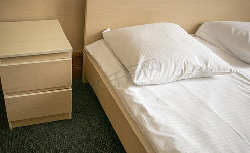 床和床头柜的特写，酒店卧室的现代而明亮的内饰