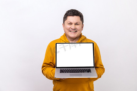 男子手持白色显示屏笔记本电脑，面带微笑地看着相机，对新操作系统感到满意。