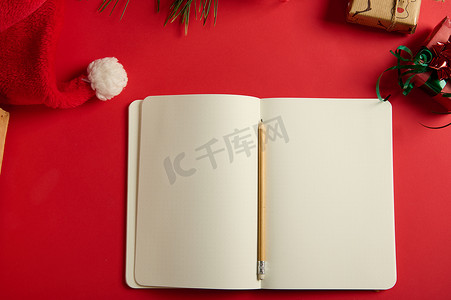 纸质红色摄影照片_静物生活，有一个开放的记事本，上面有空白纸片，红色背景上的文字复制空间，上面有圣诞物品