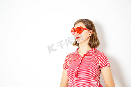 白色背景上戴着红色心形太阳镜的年轻漂亮女人的画像。