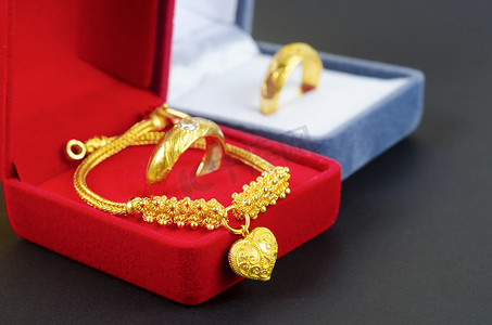 时尚吊坠摄影照片_红色天鹅绒盒子上的金项链和带戒指的心形吊坠。