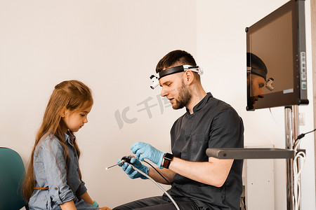 耳鼻喉科医生耳鼻喉科医生，头灯向儿童内窥镜显示，用于鼻镜检查和耳镜检查。