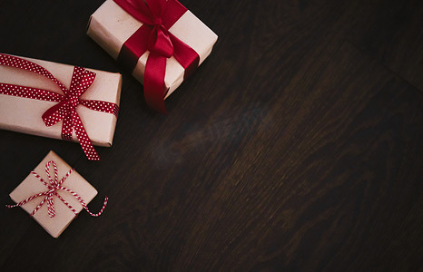 传统节日贺卡摄影照片_圣诞礼物和传统节日礼物，木制背景的经典圣诞礼盒，用红丝带工艺纸包裹的礼物，复古乡村风格的季节性假期