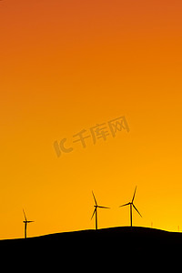 日落时站在山上发电的多台风力涡轮机