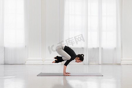 健身房运动卡摄影照片_在明亮的健身房里做瑜伽冥想的迷人女人的侧视图。