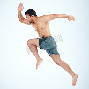 在蓝色背景模型中孤立的工作室中的人的跑步、跳跃和健身。