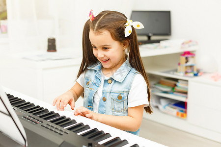 漂亮的小女孩在客厅或音乐学校弹钢琴。