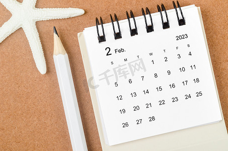 2023 年 2 月的月历，木制背景上有海星和铅笔。