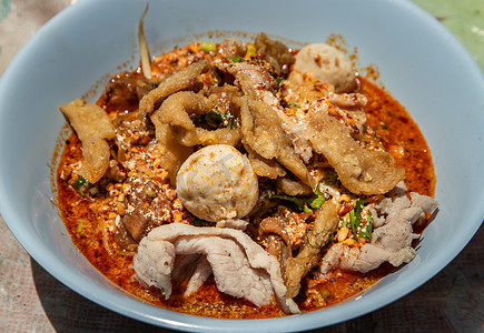 泰式辣汤鸡蛋面配红烧猪肉、猪肉丸和白碗肥猪皮。
