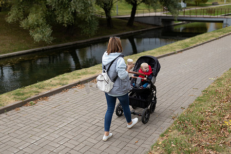 快乐的年轻母亲和她的小儿子在公园里散步