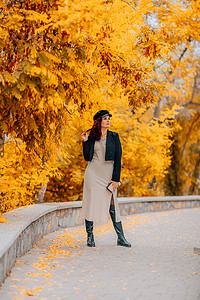 一个女人在秋天到户外散步，享受秋天的天气。