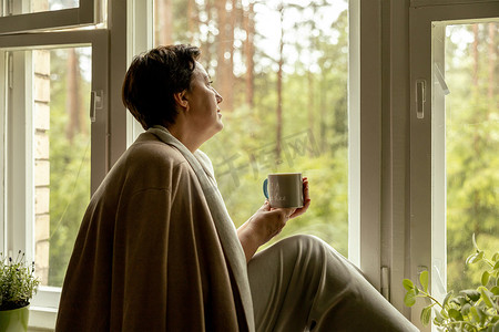 中年美女坐在窗台上，喝茶，做梦。 