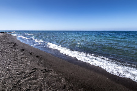 在沙滩上用黑色的火山岩沙滩冲浪。