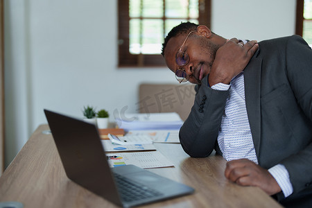 精疲力尽的美国非洲商人在压力下处理许多文书工作文件、偏头痛发作、自由职业者、在家工作