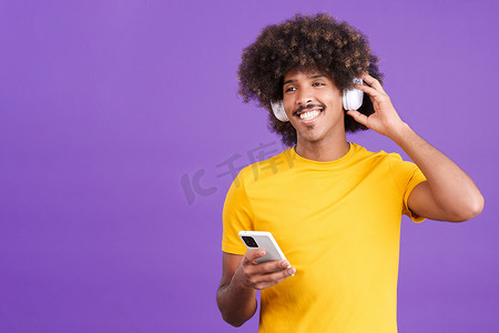 快乐的非洲男人戴着耳机和手机听音乐