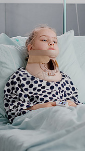 中同摄影照片_生病的儿童病人躺在床上看着相机，同时有颈部颈圈的肖像
