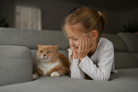 一个女孩靠近沙发上的姜猫