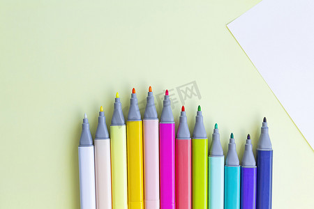 幼儿园相册摄影照片_许多彩色毡尖笔用于在黄色背景上的笔记本和相册中绘图。