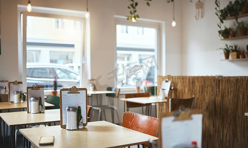 新店开业限时特惠摄影照片_城市一家空荡荡的咖啡店里的桌子、椅子和菜单准备在开业当天提供服务。