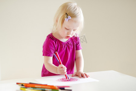 可爱的蹒跚学步的女孩用彩色铅笔画画