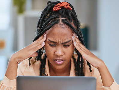 黑人女性在家办公时因笔记本电脑故障而头痛和压力大。